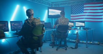 Active-duty-soldiers-in-dark-blue-lit-room-at-computers-341x180